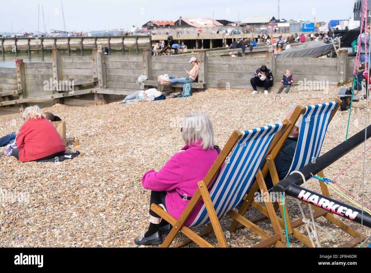 People sitting on beach deck chairs enjoy the sunny weekend, Whitstable