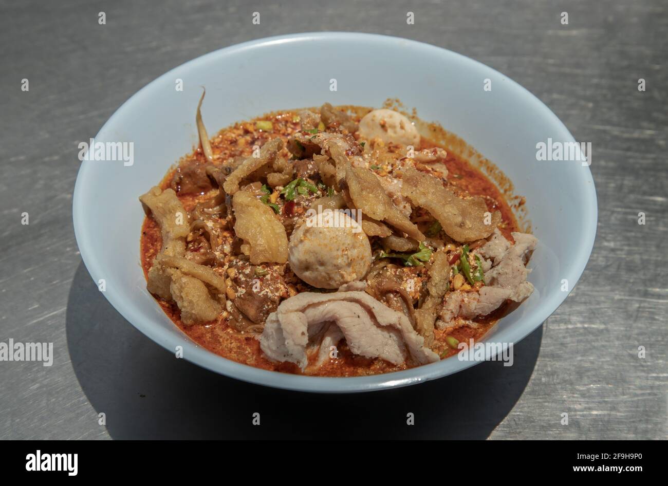 Egg noodles in Thai spicy soup with braised pork, pork balls and fatty