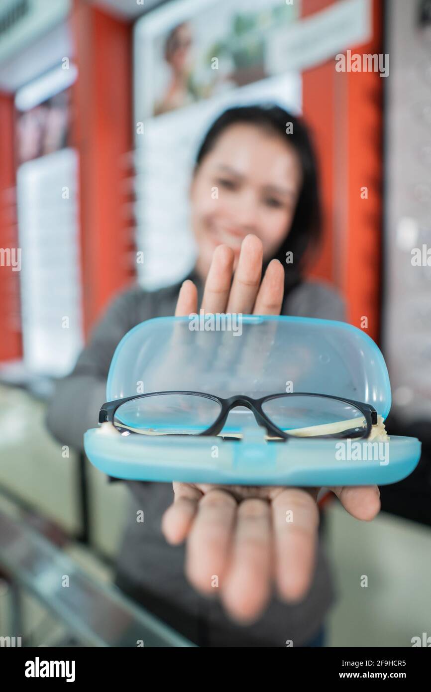selective focus of the glasses in the eyeglass box with the background of a beautiful smiling woman Stock Photo