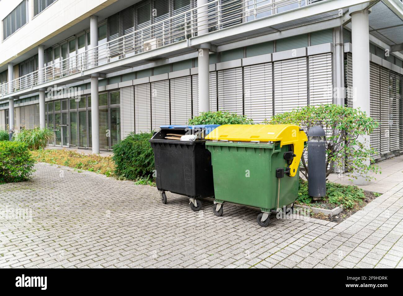 Two plastic clean garbage containers black and greenyellow for
