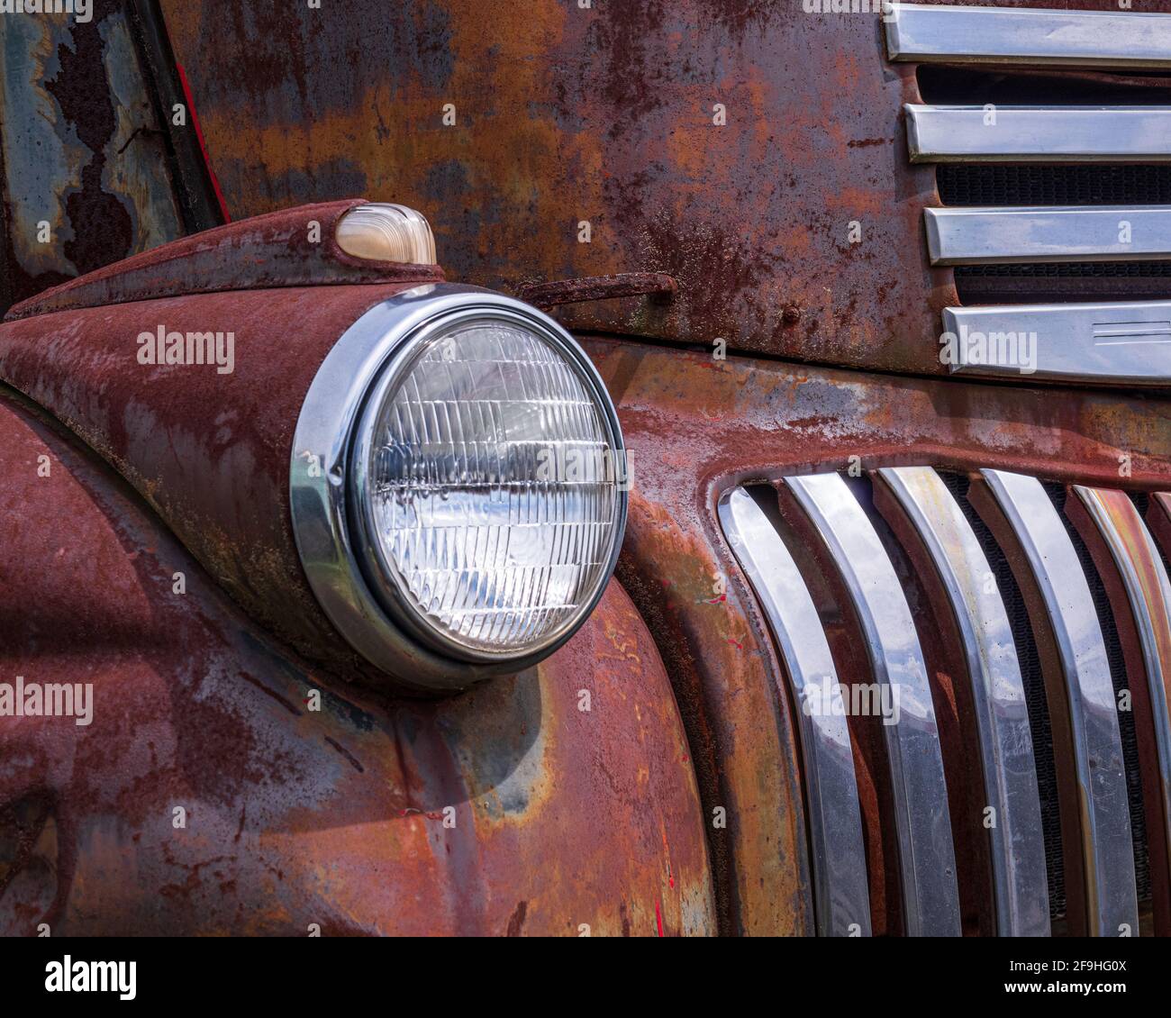 Headlight and partial shot of grill of antique, rusted red Chevrolet truck Stock Photo