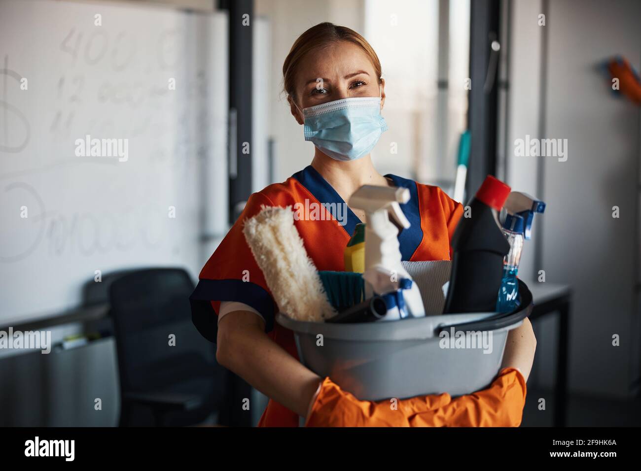 Cleaner in a face mask showing her cleaning products Stock Photo Alamy