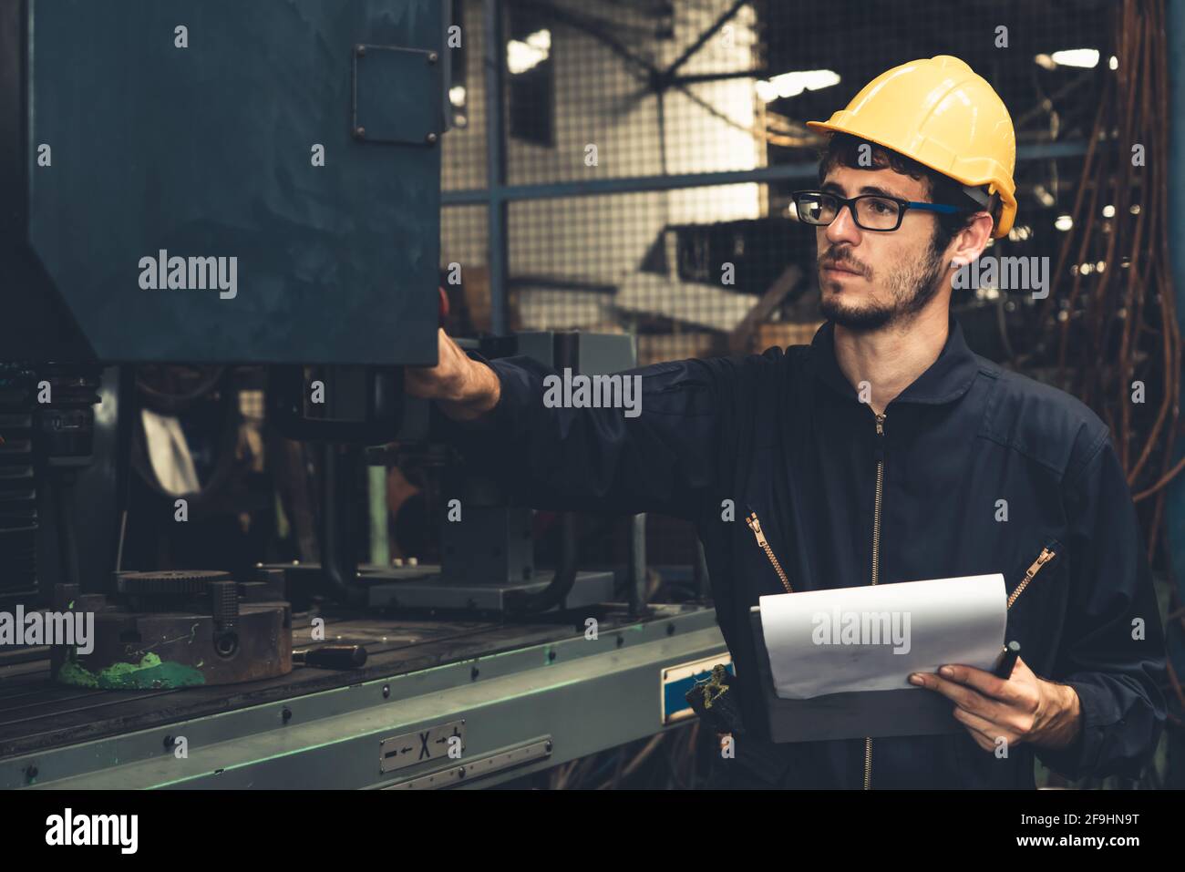 Skillful factory worker working with clipboard to do job procedure