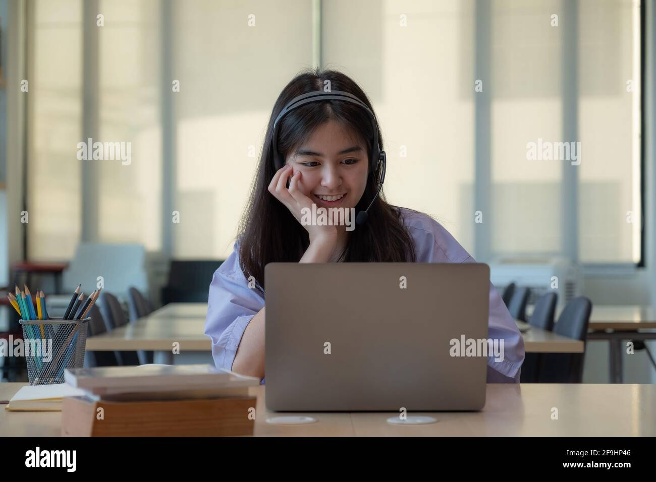 Portrait young asian girl looking camera while using laptop computer ...