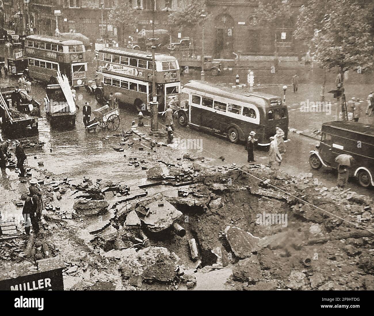 WWII - German Bombing raids on London, UK (Blitz)  in September 1940 - Vintage London buses drive past a bomb crater in the Strand. Stock Photo