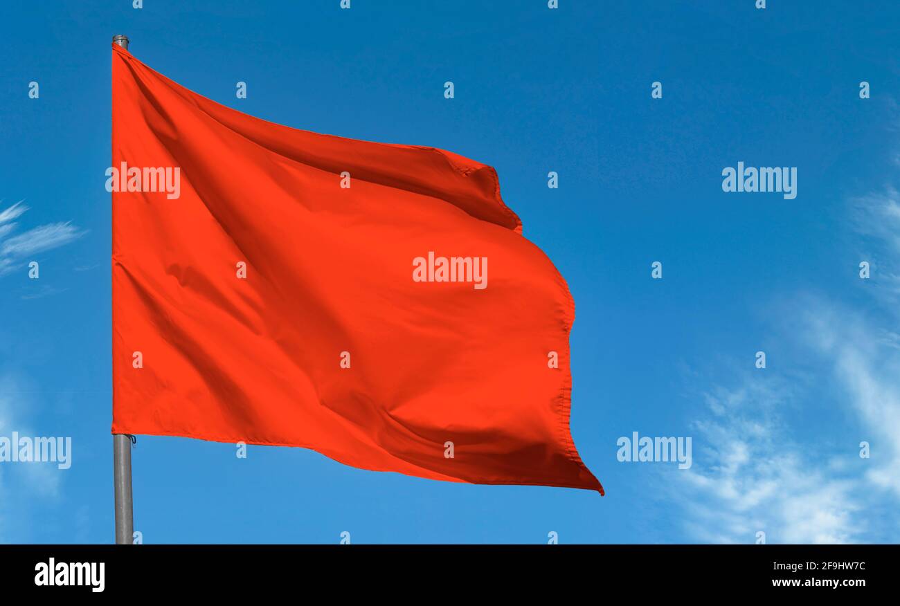 Bright red flag waving against blue sky, blank red banner Stock Photo