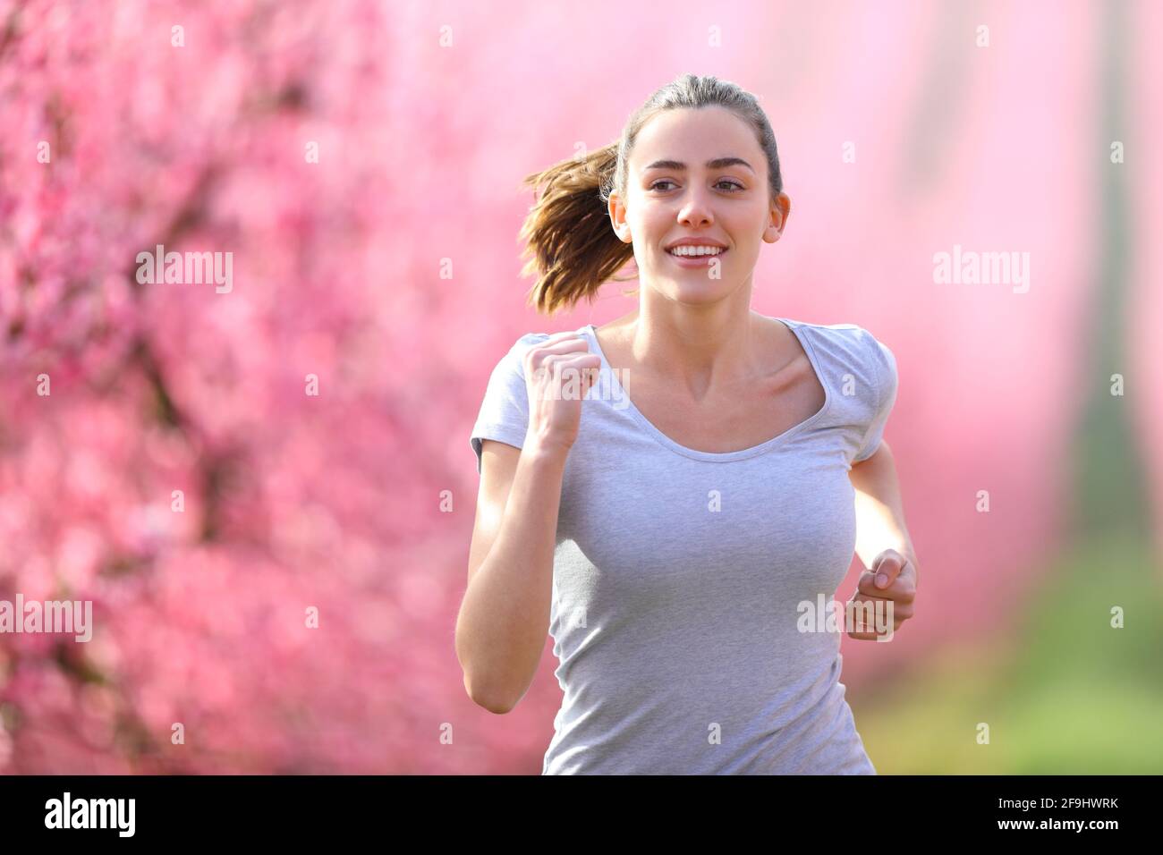 Front view portrait of a happy woman running in a flowered field towards camera Stock Photo