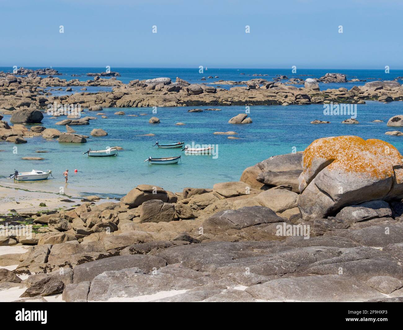 Small fishing boats at anchor in a cove on the rocky coast of northern Finistère in Brittany. Stock Photo
