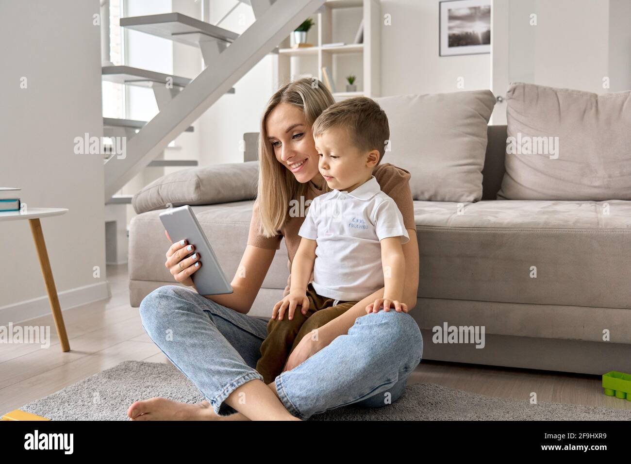 Happy family mom and cute child son holding digital tablet at home. Stock Photo