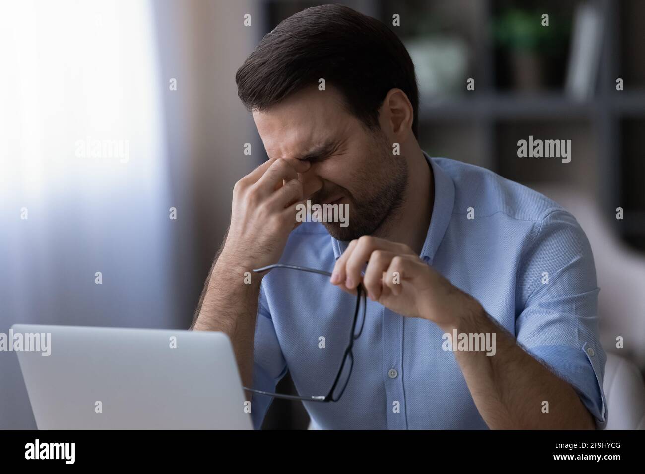 Exhausted man suffer from headache working on laptop Stock Photo