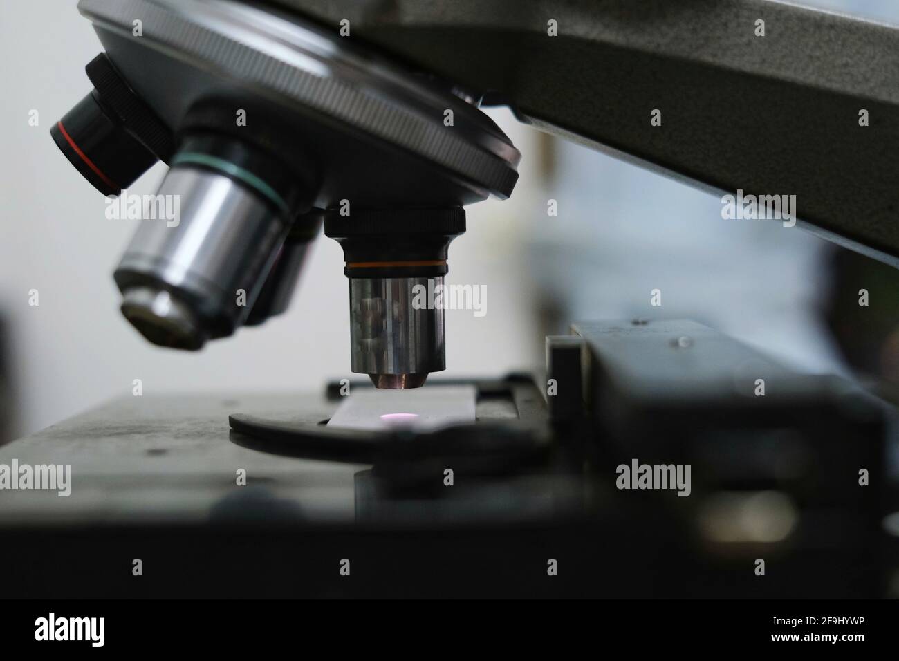 A close up picture of objective lens and stage of a microscope made from metal and glass in a laboratory. Stock Photo