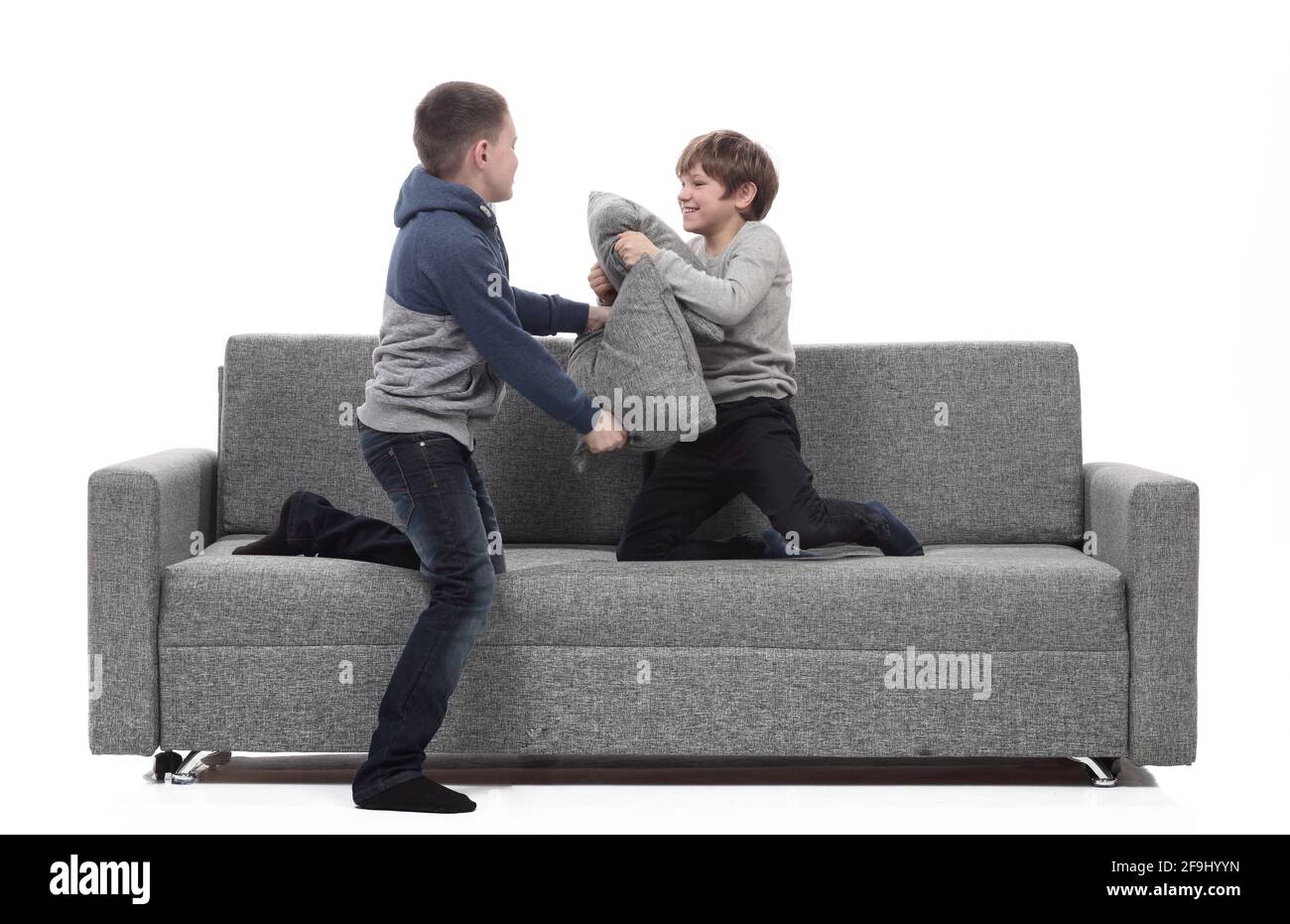 two brothers have a pillow fight on the couch. Stock Photo
