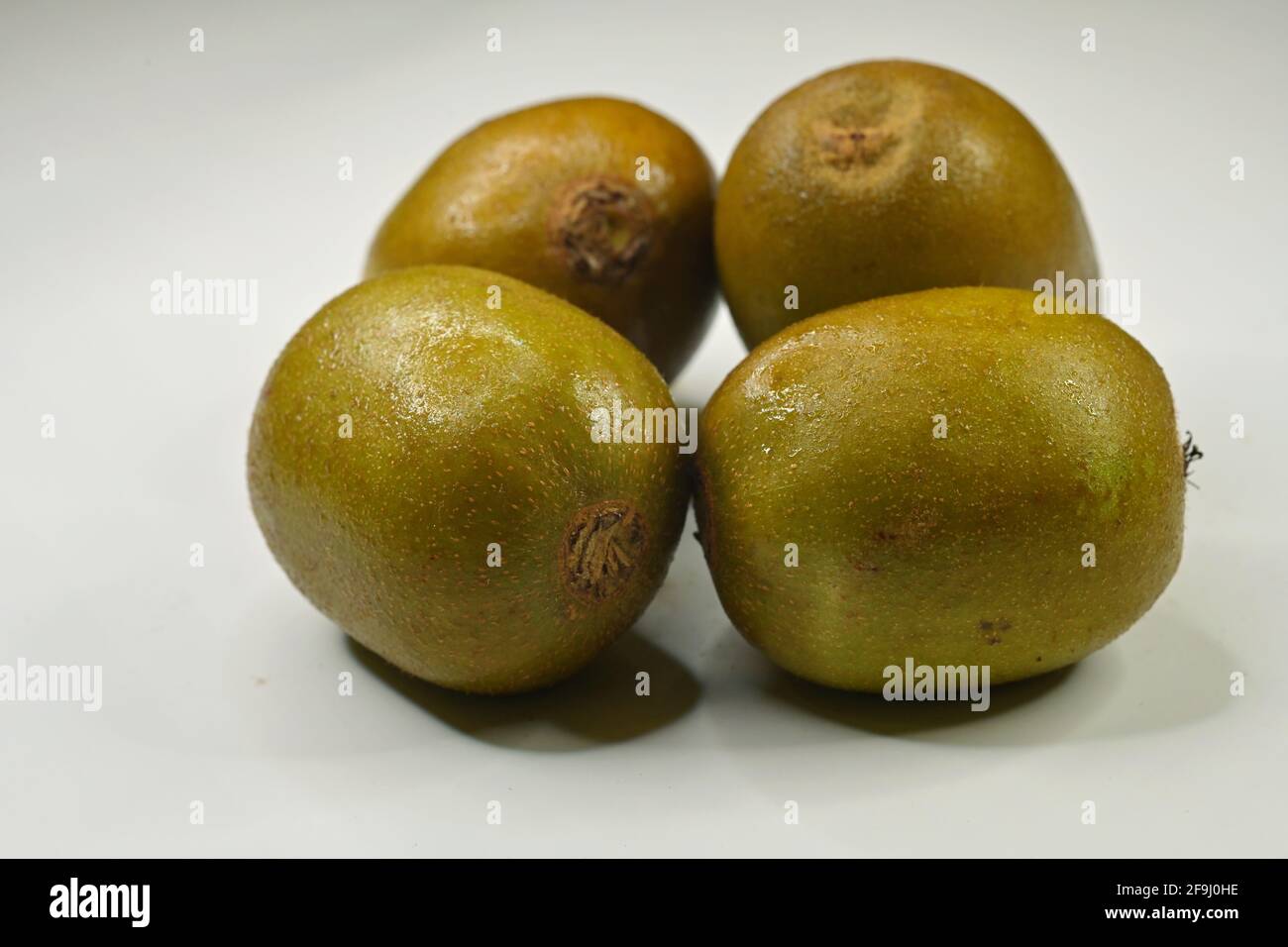 Bunch of red Kiwifruit or Chinese gooseberry (genus Actinidia) on white background. The red kiwifruit is said to be sweeter, juicy and less astringent Stock Photo