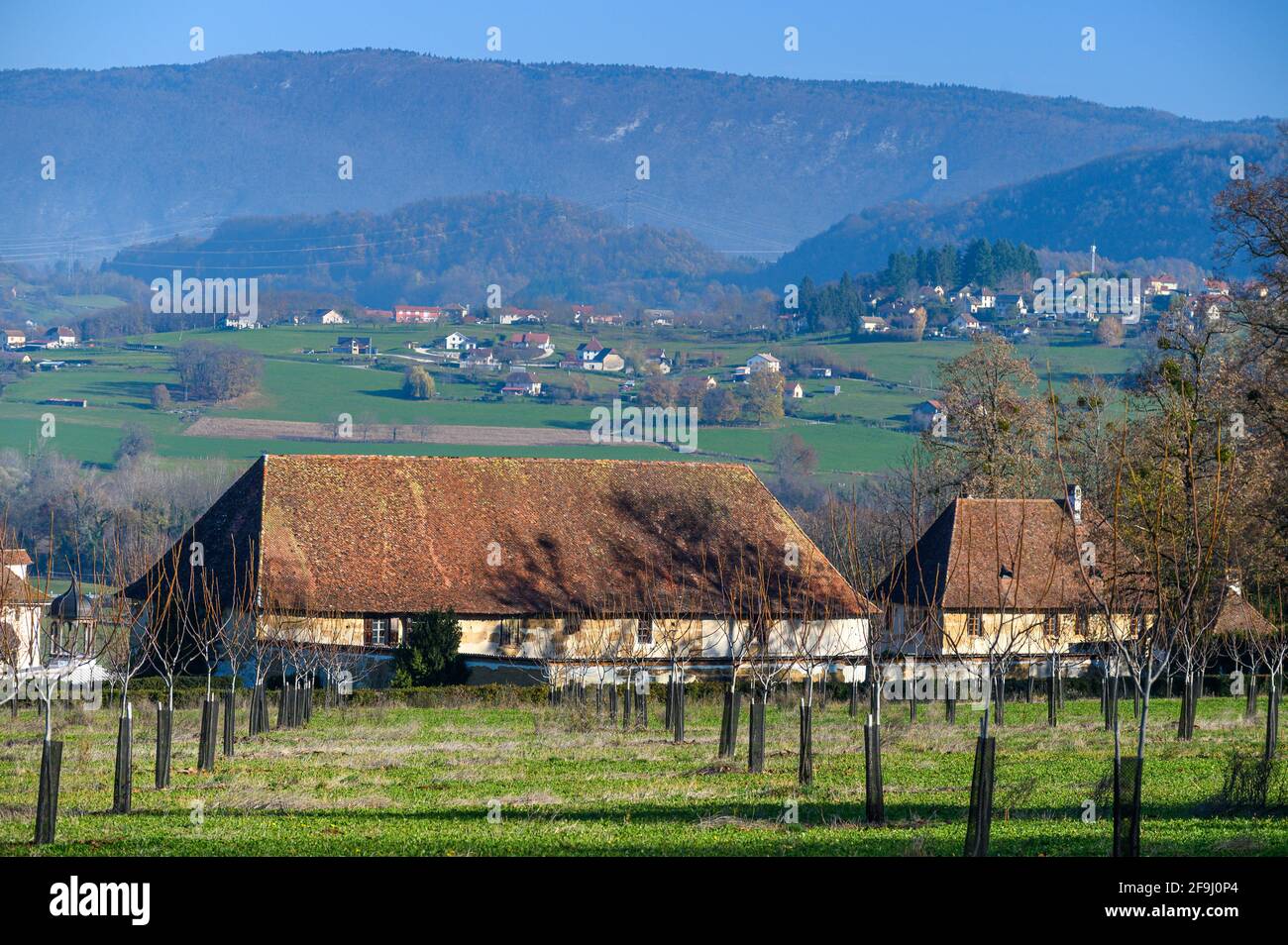 Wide view of french rural house in Front of a barn featuring mountain village in backdrop Stock Photo