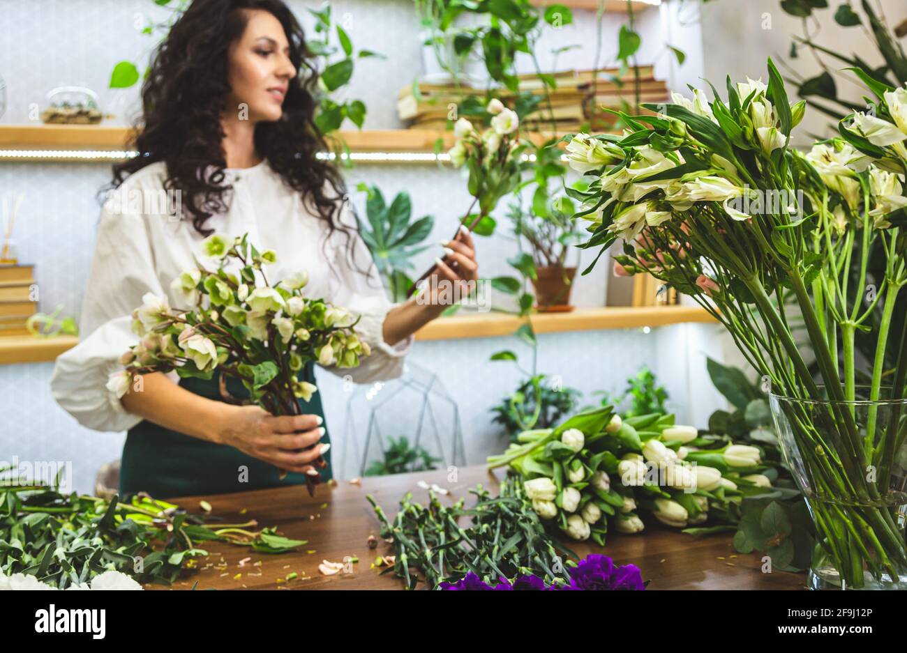 Attractive young woman florist is working in a flower shop Stock Photo ...