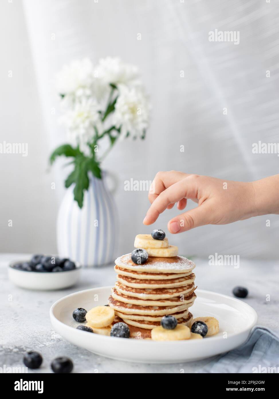 childrens hand and stack of pancakes with berries. delicious homemade breakfast. vertical image Stock Photo