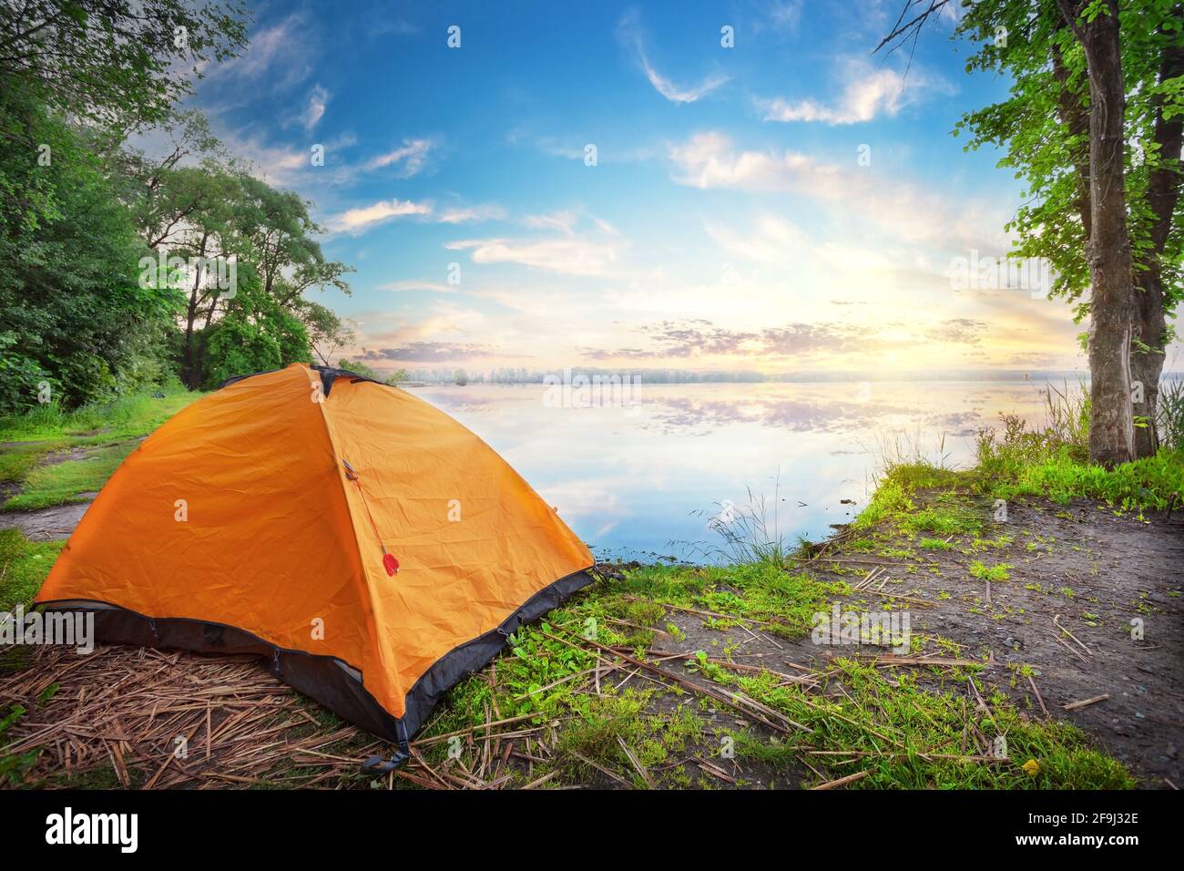 Orange tent by the lake at the sunset Stock Photo