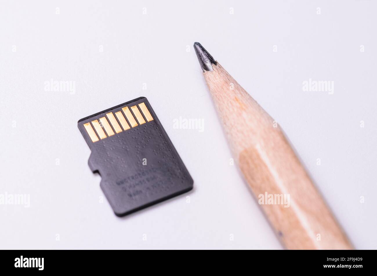 Micro SD memory card and wooden pencil for size comparison, isolated on white background Stock