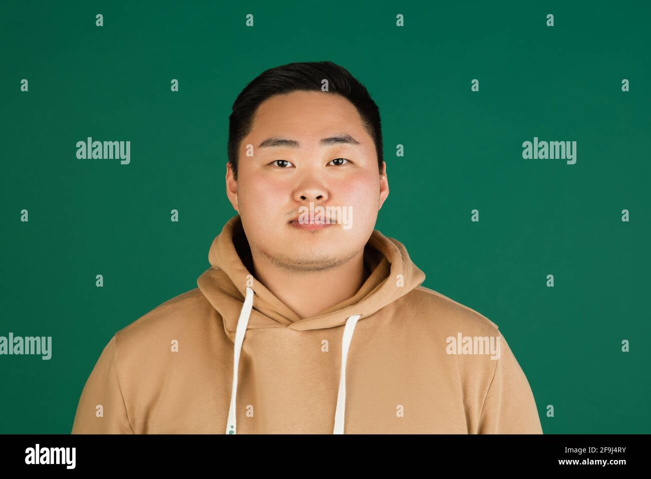 Asian man's portrait isolated over green studio background with ...