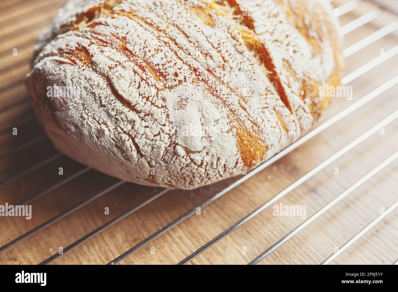 Freshly baked loaf of sourdough bread cooling on a cooling rack on a ...
