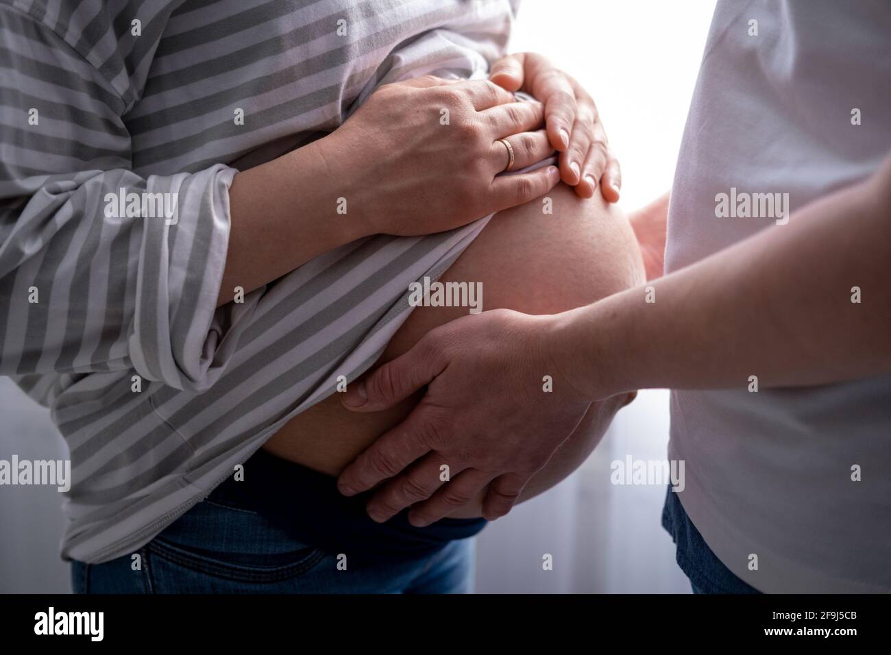 close up hands on mother and father making heart on pregnant big belly