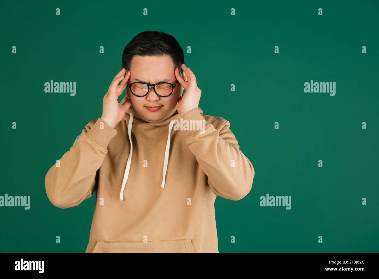 Asian man's portrait isolated over green studio background with ...