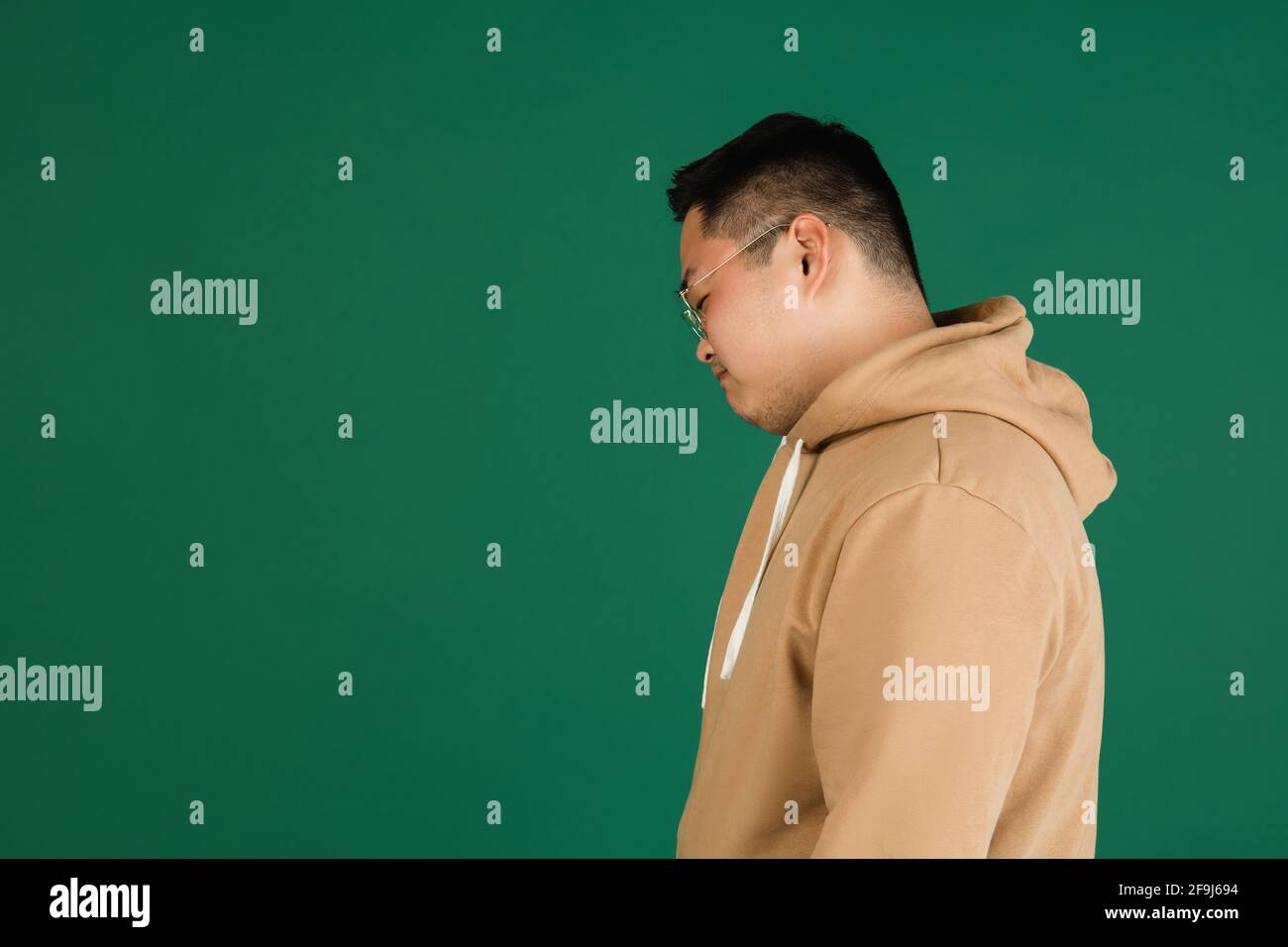 Asian man's portrait isolated over green studio background with ...