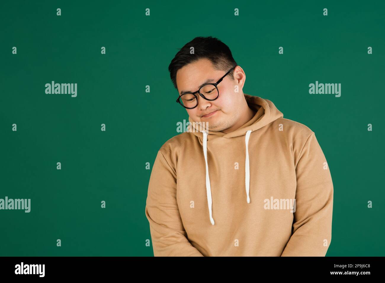 Asian man's portrait isolated over green studio background with ...