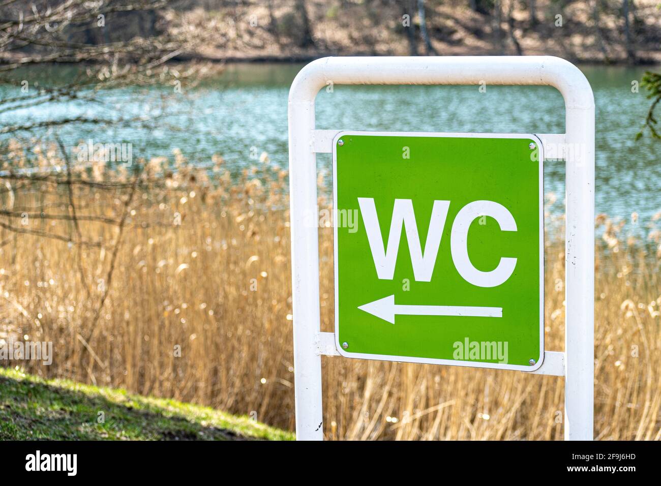 WC logo, sign of public toilet against nature background with arrow. Toilet, washroom and bathroom Stock Photo