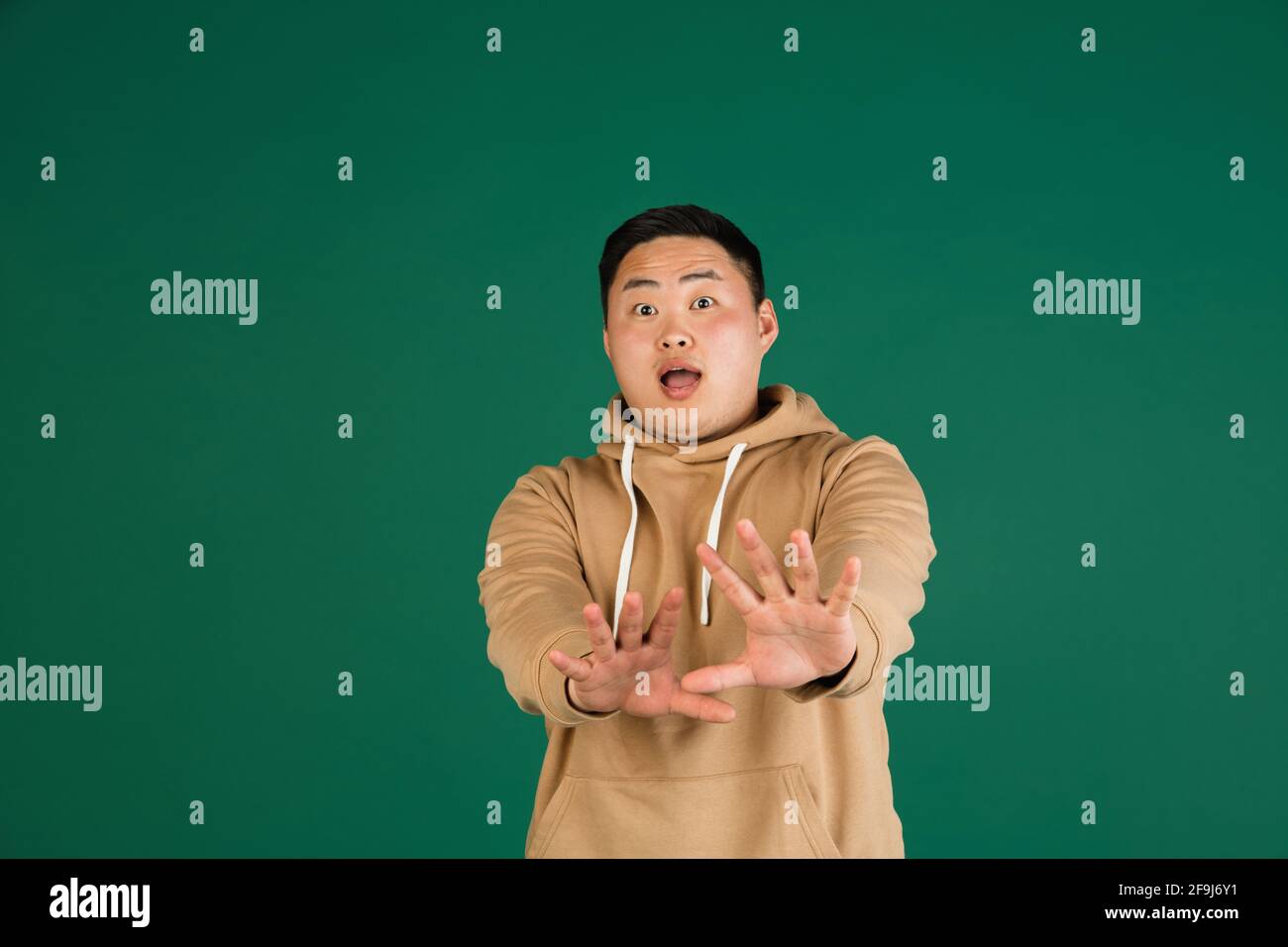 Asian man's portrait isolated over green studio background with ...
