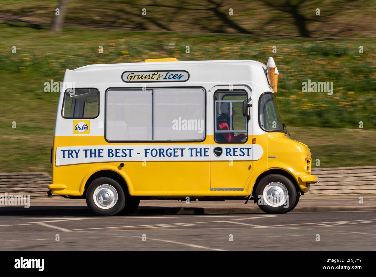 Ice Cream van driving in Southend on Sea, Essex, UK, on a sunny, bright Spring day. Grant's Ices. Try the best, forget the rest, slogan. 1980 Bedford Stock Photo