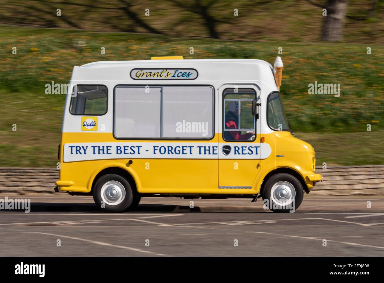 Ice Cream van driving in Southend on Sea, Essex, UK, on a sunny, bright Spring day. Grant's Ices. Try the best, forget the rest, slogan. 1980 Bedford Stock Photo