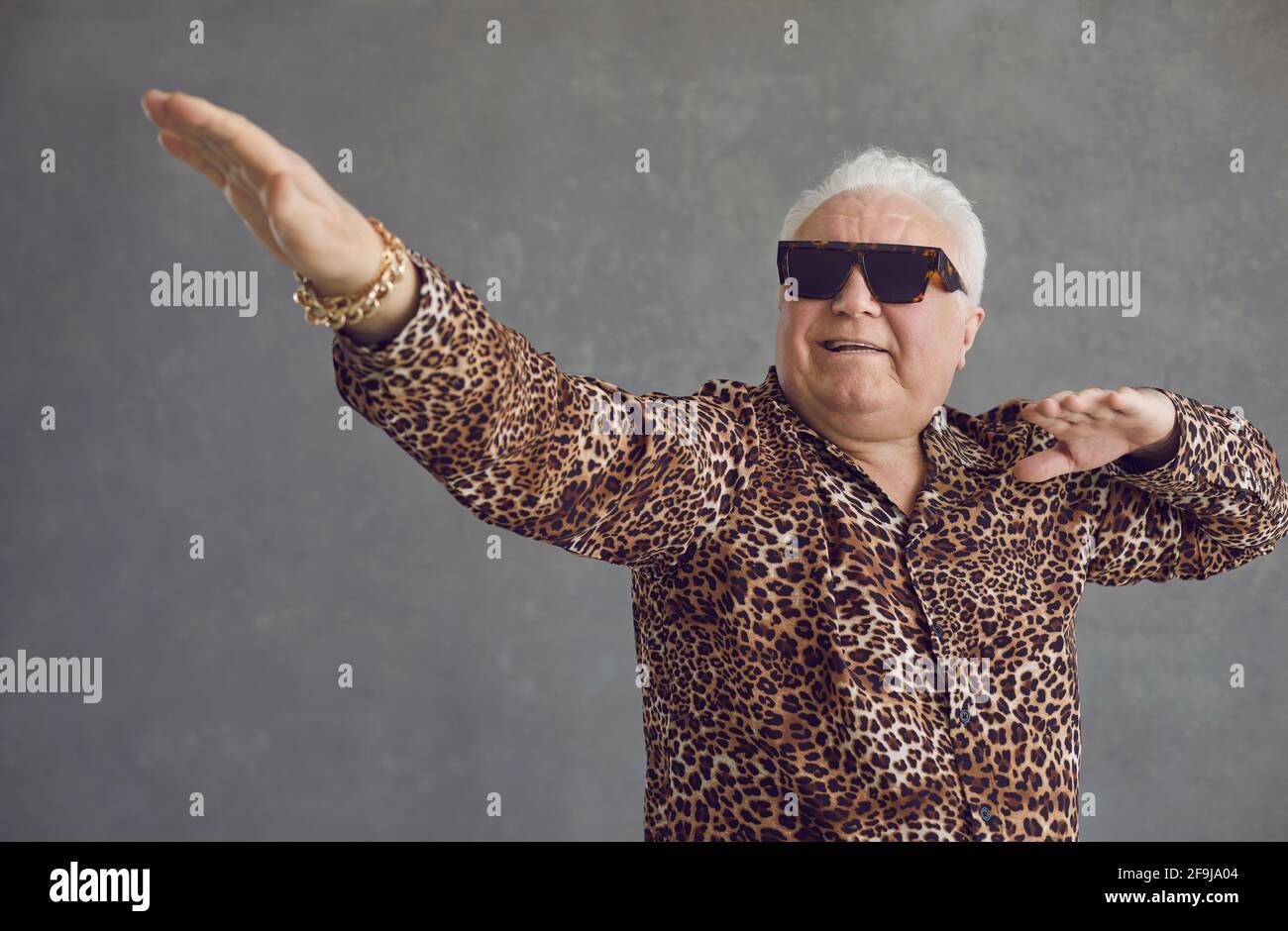 Studio portrait of funny dancing rich senior man in leopard shirt and cool glasses Stock Photo