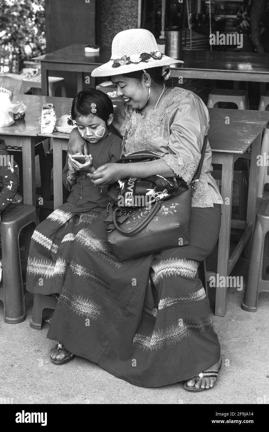 A Burmese Grandmother Looks On With Pride As Her Granddaughter Uses A Mobile Phone (Cellphone), Pindaya, Shan State, Myanmar. Stock Photo
