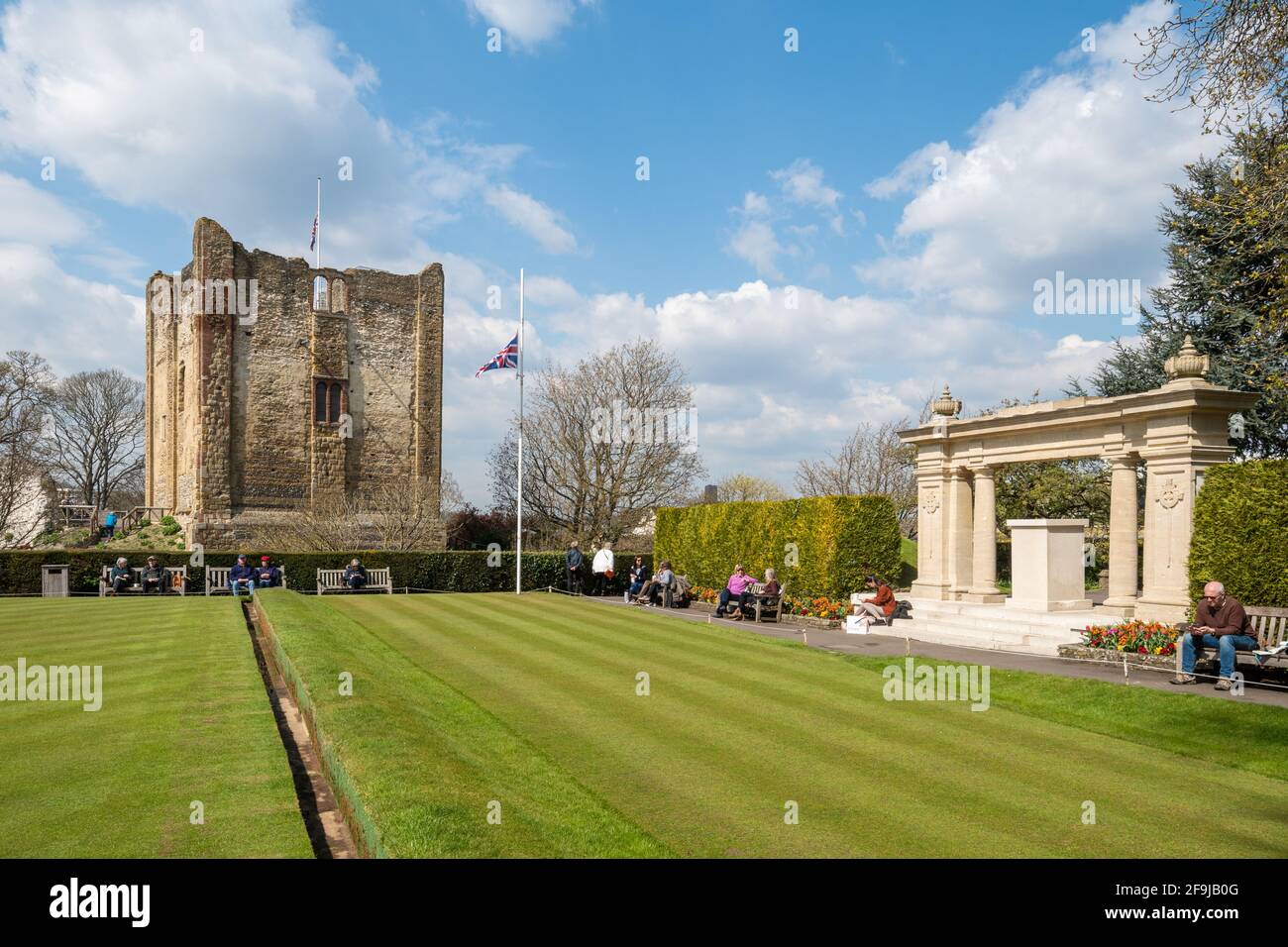 Guildford Castle grounds with people enjoying a warm spring day by the bowling green and war memorial  Surrey, England, UK Stock Photo