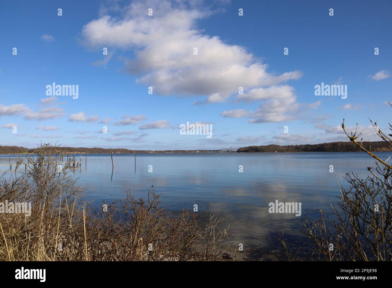 Landscape of a lake surrounded by fields under a blue cloudy sky in ...