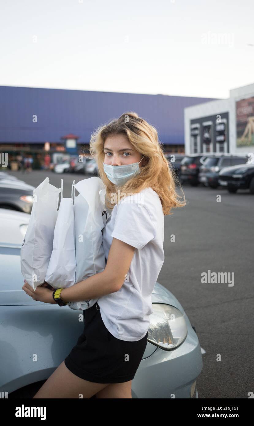 young woman in a protective medical mask on her face with packages ...