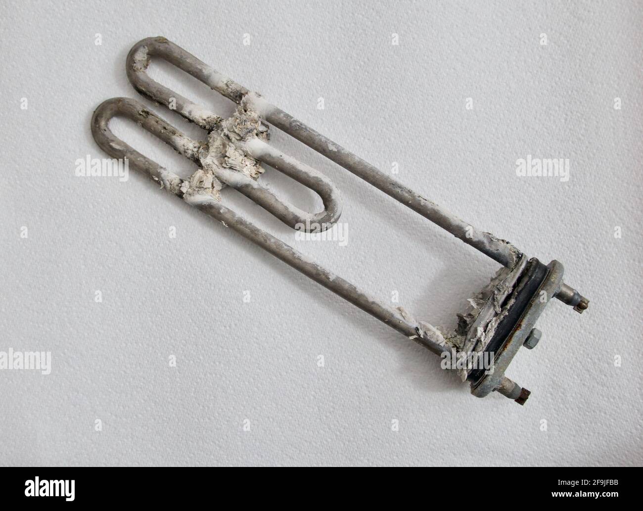 Charred and scaled heating element from washing machine on white