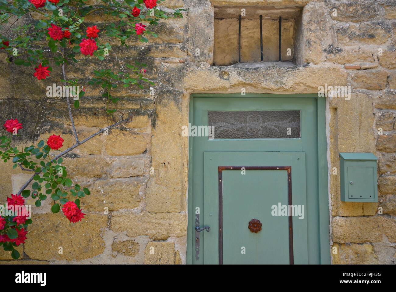 Provençal style rural house facade with an olive green door on a stone wall in the picturesque village of Lourmarin in Vaucluse, Provence France. Stock Photo
