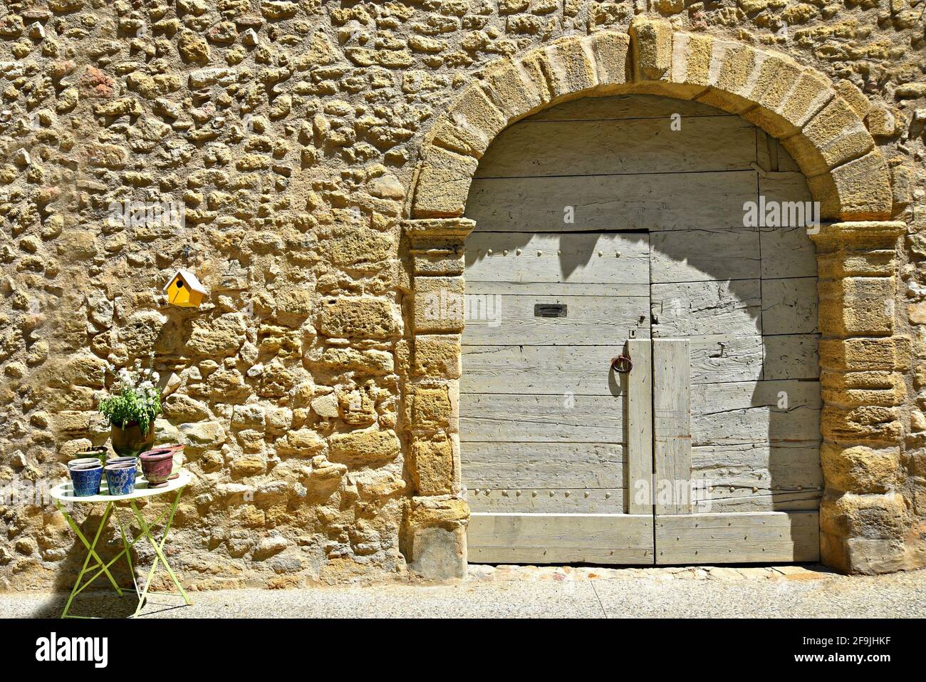 Provençal style house facade with an arched antique wooden door on a stone wall in the picturesque village of Lourmarin in Vaucluse, Provence France. Stock Photo