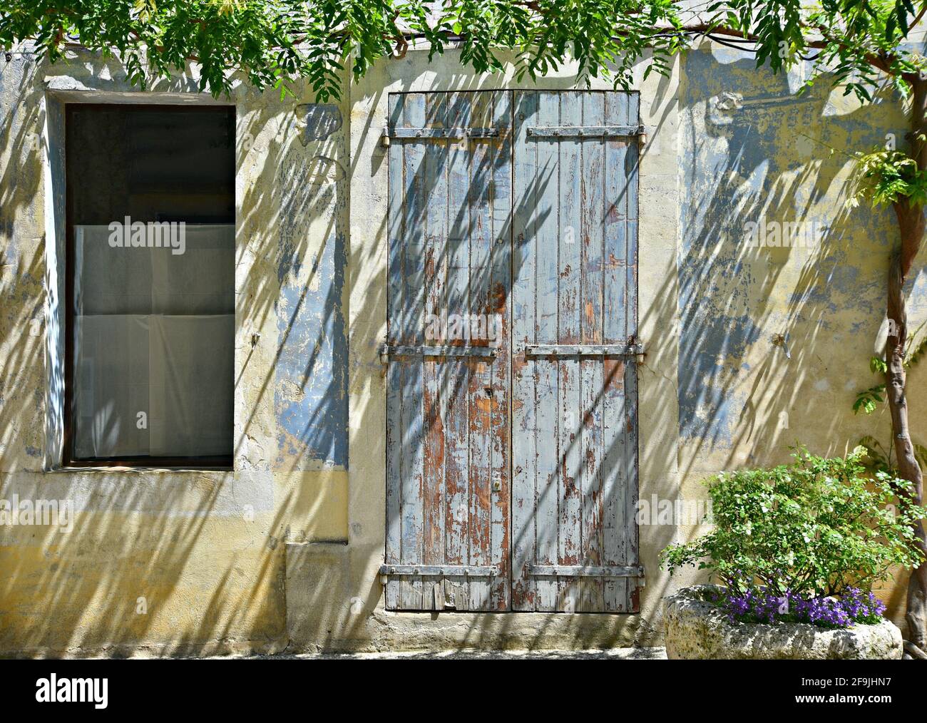 Typical Provençal style rural house facade with an antique grey  wooden door in the picturesque village of Lourmarin in Vaucluse, Provence France. Stock Photo