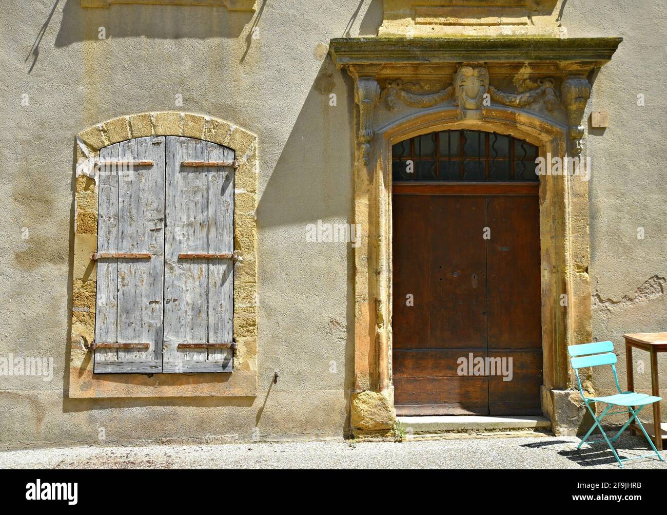 Local Haute Couture shop facade with an antique oak door and grey wooden shutters in the picturesque village of Lourmarin in Vaucluse Provence France. Stock Photo