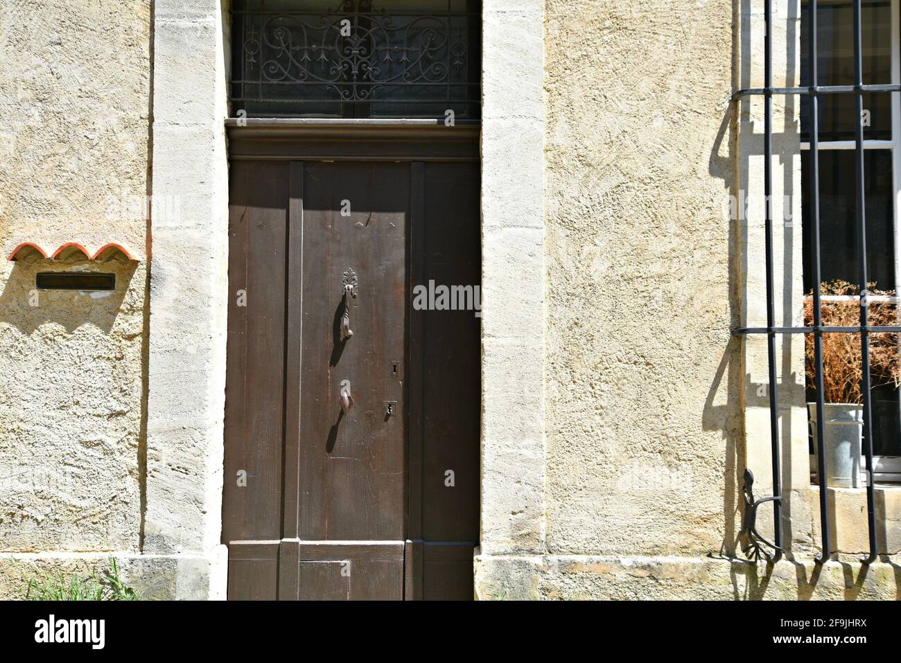 Typical Provençal style rural house facade with a brown wooden door  in the picturesque village of Lourmarin in Vaucluse, Provence France. Stock Photo