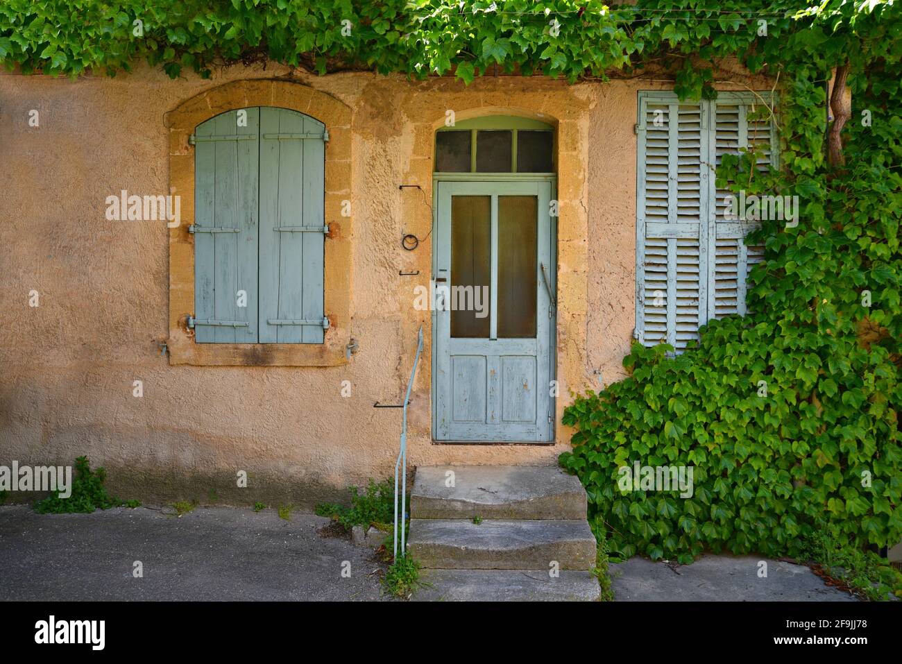 Typical Provençal style rural house facade with Vermont green door and shutters in the picturesque village of Lourmarin in Vaucluse, Provence France. Stock Photo