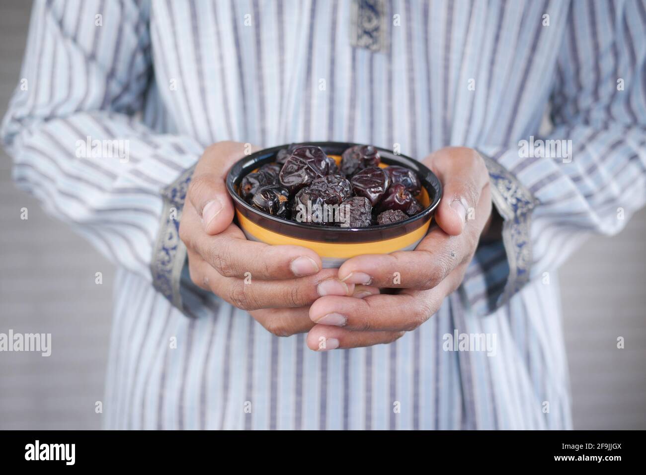 the concept of ramadan, hand holding a bowl of date fruits  Stock Photo