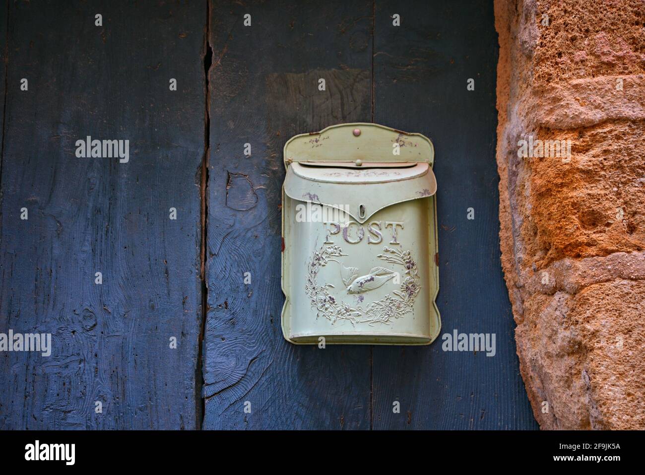 Handcrafted retro metal mailbox on a weathered blue wooden door in the picturesque village of Lourmarin in Vaucluse Provence-Alpes-Côte d'Azur France. Stock Photo