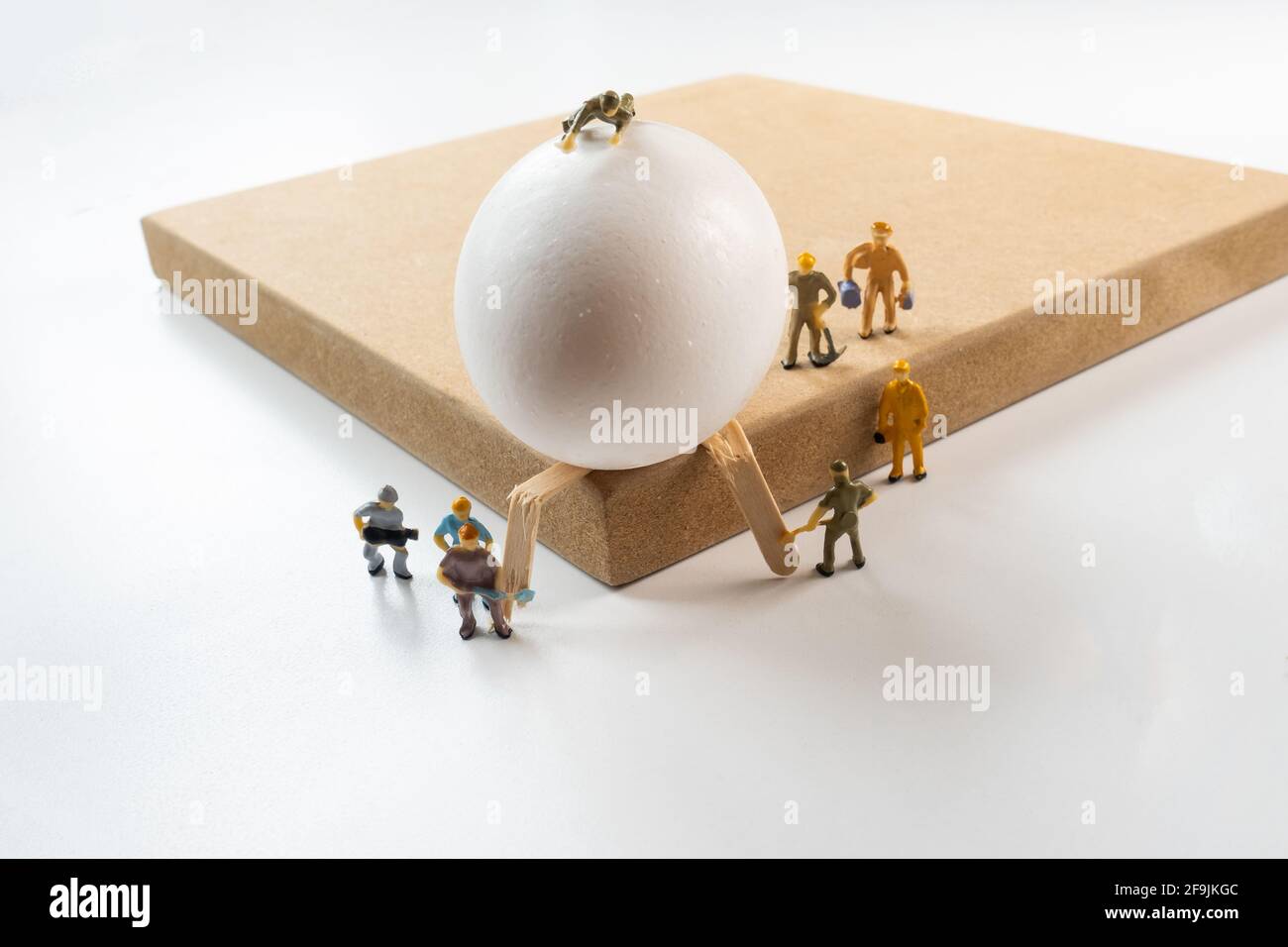 The Egg going to fall down and figure workers trying to stop it,  emergency situation, disaster recovery, team work concept Stock Photo