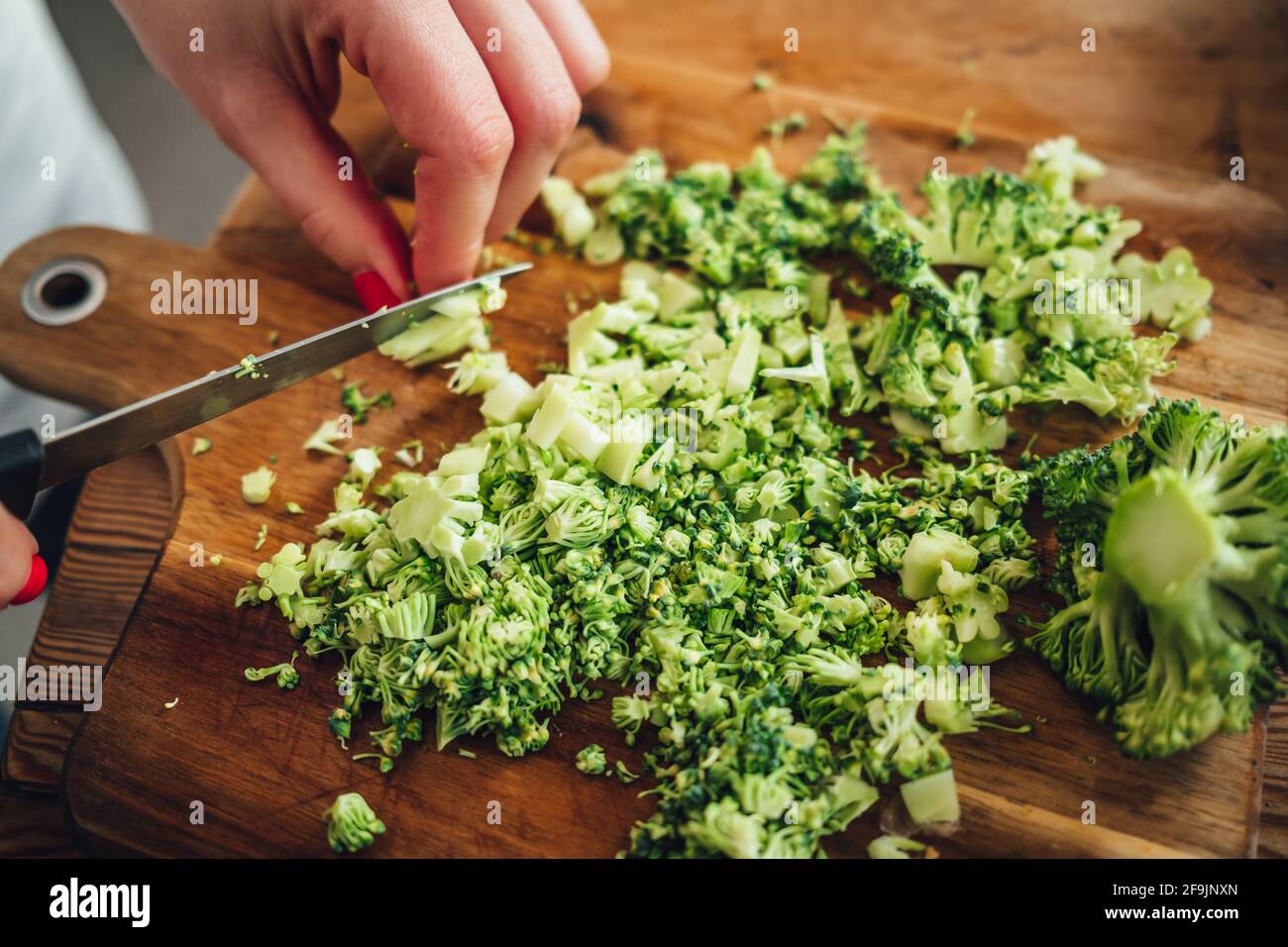 Closeup of a female chopping the fresh and tasty broccoli with a knife ...