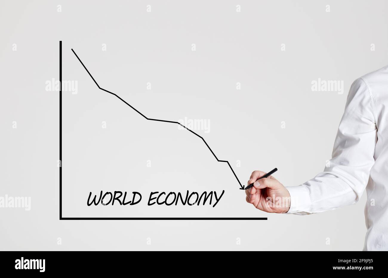 Businessman draws a declining line graph with the word world economy ...