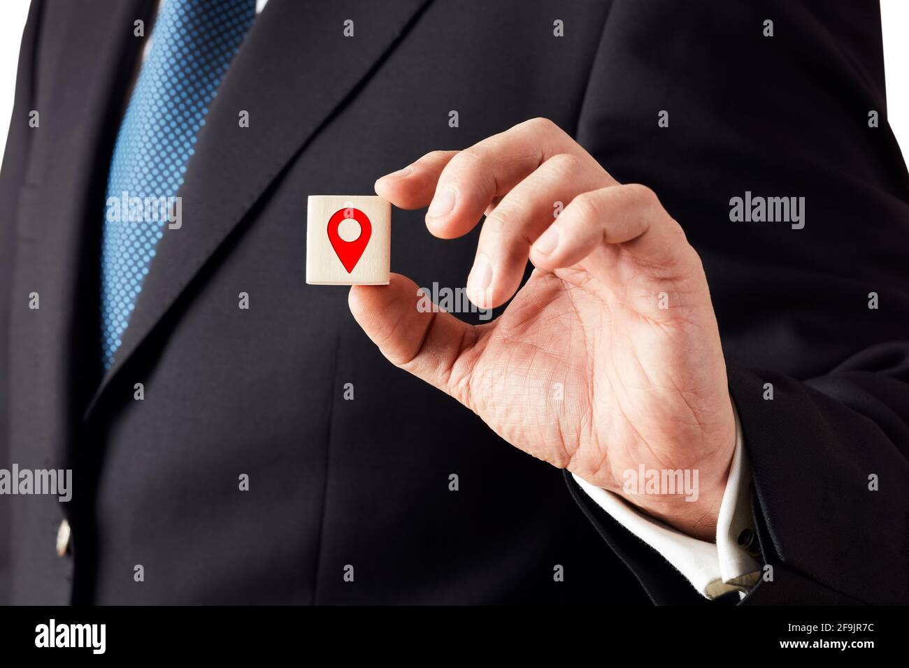 Businessman shows a wooden cube with a map pin location icon. Stock Photo